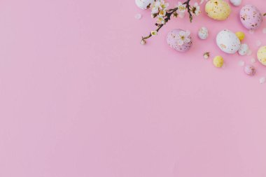Mutlu Paskalyalar! Renkli Paskalya çikolatası yumurtaları ve kiraz çiçekleri pembe arka planda sınırdır. Paskalya düzlüğü, yazı için yeri vardı. Yumuşak bahar pankartı şablonu. Tebrik kartı