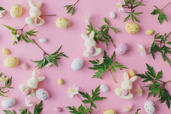 ハッピーイースター カラフルなイースターチョコレートの卵 バニー 春の花はピンクの背景に平ら スタイリッシュなイースターレイアウト グリーティングカードやバナー 飴と花の構図 — ストック写真