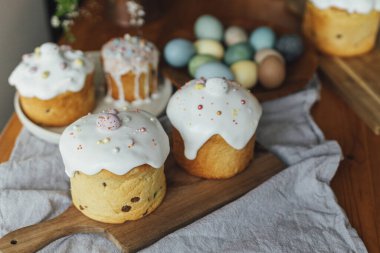 Ev yapımı Paskalya ekmekleri, doğal boyanmış yumurtalar ve kırsal masada bahar çiçekleri. Mutlu Paskalyalar! Şekerli ve serpiştirilmiş taze paskalya pastası, geleneksel Ukrayna çöreği.