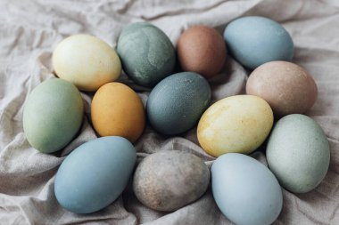 Mutlu Paskalyalar! Paskalya yumurtaları kırsal çarşaf peçetesinde. Doğal boyalı pastel renkli yumurta kompozisyonu. Kırsal yaşam, üst görünüm