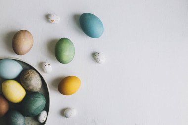 Kırsal beyaz ahşap arka planda süslü Paskalya yumurtaları, metin için yeri olan düz bir yer. Mutlu Paskalyalar! Kırsal masada doğal renkli yumurta kompozisyonu.
