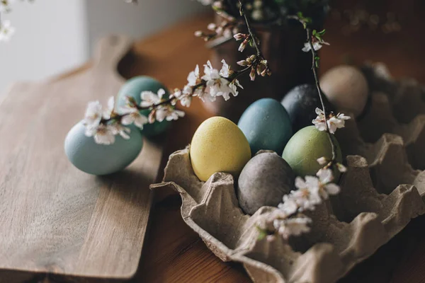 复活节快乐 复活节彩蛋放在带有樱花的乡村餐桌上 木制木板纸盘上的彩蛋是天然染色的 乡村室内的春花也是天然染色的 喜怒无常的大气图像 — 图库照片