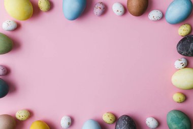 Kaliteli yumurtalar pembe arka planda yatıyordu. Modern doğal boyalı paskalya yumurtaları ve çikolata şekeri pembe çerçeveli. Tebrik kartı şablonu, metin için boşluk