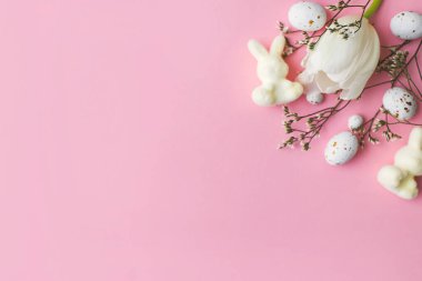 Şık yumurtalar, laleler, tavşanlar pembe arka planda yatıyordu. Modern çikolatalı paskalya yumurtaları ve beyaz lalelerin düzeni. Tebrik kartı şablonu, paskalya arkaplanı. Metin için boşluk