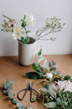 Ahşap pencere pervazında seramik vazoda şık bir buket. Ahşap arka planda güzel taze çiçekler ve makas, çiçek aranjmanı. Bahar modern buket