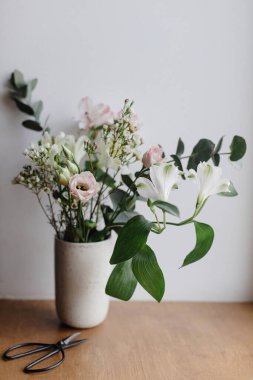 Ahşap pencere pervazında seramik vazoda şık bir buket. Ahşap arka planda güzel taze çiçekler ve makas, çiçek aranjmanı. Bahar modern buket