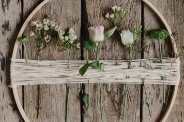 Taze çiçekli şık bahar çelengi. Çiçekli ahşap halka ve kırsal ahşap arka planda iplik. Modern ve yaratıcı el yapımı çiçek dekoru