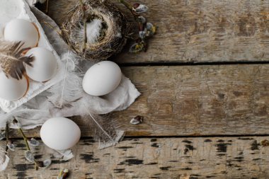 Paskalya kırsalı düzlüğü, yazı için boşluk. Tepside doğal yumurtalar, tüyler, söğüt dalları, eski ahşap masaya yuva. Paskalya kırsalındaki şık yaşam. Pastel kahverengi renklerde basit estetik.