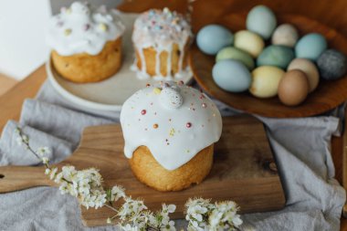 Mutlu Paskalyalar! Ev yapımı paskalya ekmeği, doğal boyanmış yumurtalar ve kırsal masada bahar çiçekleri. Şekerli ve serpiştirilmiş taze paskalya pastası, geleneksel Ukrayna çöreği.