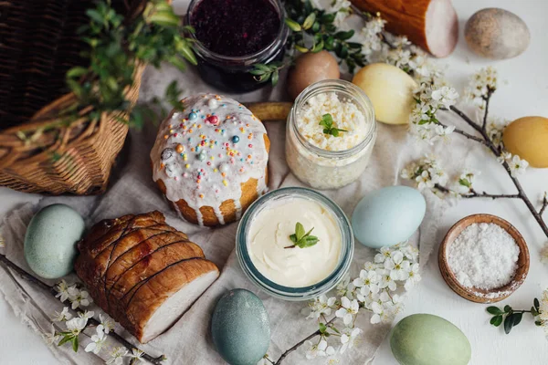 传统的复活节篮子食物 采购产品天然染色的复活节蛋 时尚的复活节面包 奶酪在乡村木桌上 与春天的花朵和亚麻布餐巾 顶部视图 — 图库照片