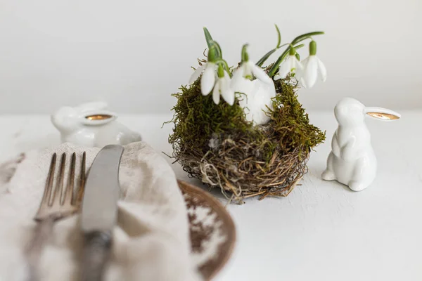 スタイリッシュなイースターテーブルの設定 現代的なプレート ナプキン カトラリー 白い木のウサギの雪滴と天然の卵 現代のイースターテーブルの装飾 — ストック写真