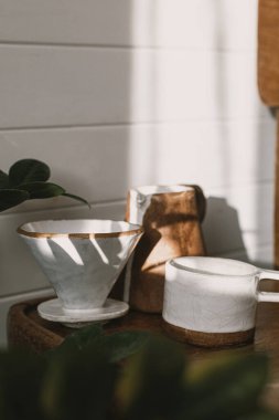 Modern seramik fincan, çaydanlık ve damlatıcı kırsal ahşap sandalyeye güneş ışığında kahve dökmek ve şık güneşli odada gölgeler bırakmak için. Alternatif kahve demleme yöntemi.