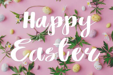 Mutlu Paskalya tebrik kartları. Mutlu Paskalya metinleri ve pembe arka planda renkli Paskalya çikolataları ve bahar çiçekleri düzeni. Mevsimlik tebrik kartı, el yazması mektuplar.