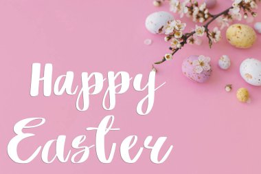 Mutlu Paskalya tebrik kartları. Mutlu Paskalya metinleri ve renkli Paskalya çikolataları ve pembe arka planda kiraz çiçekleri. Mevsimlik tebrik kartı, el yazması mektuplar.