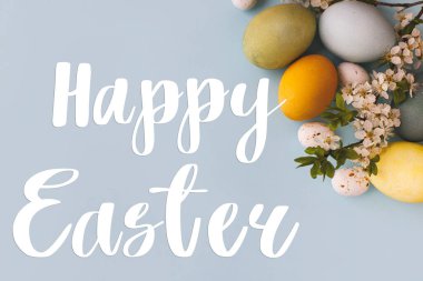 Mutlu Paskalya metinleri ve modern stil mavi ve sarı paskalya yumurtaları, kiraz çiçekleri mavi arka planda yatıyordu. Mutlu Paskalya tebrik kartları. Mevsimlik tebrik kartı, el yazması mektuplar.