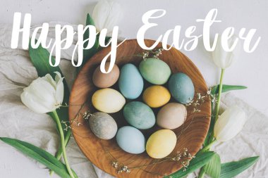 Mutlu Paskalya tebrik kartları. Mutlu Paskalya metinleri ve ahşap tabakta şık Paskalya yumurtaları, laleler, kırsal masada keten peçeteler, düz yatak. Mevsimlik tebrik kartı, el yazması mektuplar.