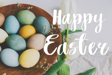 Mutlu Paskalya tebrik kartları. Mutlu Paskalya metinleri ve ahşap tabakta şık Paskalya yumurtaları, laleler, kırsal masada keten peçeteler. Mevsimlik tebrik kartı, el yazması mektuplar.