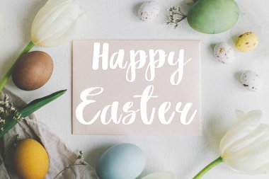 Mutlu Paskalya tebrik kartları. Paskalya mesajınız ve tebrik kartınız kutlu olsun. Paskalya yumurtaları ve beyaz ahşap laleler, düz yatak. Mevsimlik tebrik kartı, el yazması mektuplar.