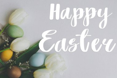 Mutlu Paskalya tebrik kartları. Mutlu Paskalya metinleri ve taşralı beyaz ahşap arka planda şık paskalya yumurtaları ve laleler. Mevsimlik tebrik kartı, el yazması mektuplar..