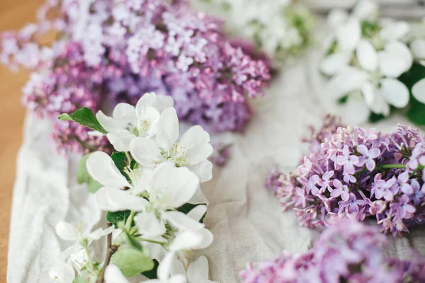Güzel leylak çiçekleri, elma çiçekleri ve keten kumaşta taç yaprakları. Kırsal alanda bahar çiçekleri hala hayat dolu. Taç yaprakları kapanıyor. Anneler günün kutlu olsun.