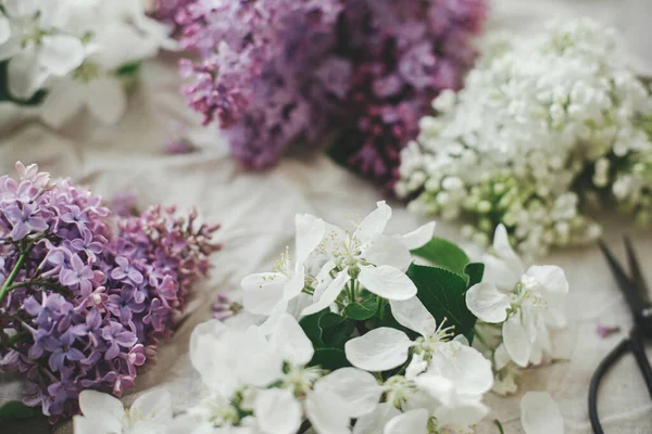 Güzel leylak çiçekleri, elma çiçekleri ve keten kumaşta taç yaprakları. Kırsal alanda bahar çiçekleri hala hayat dolu. Taç yaprakları kapanıyor. Anneler günün kutlu olsun.