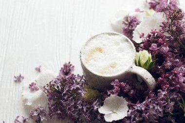 Lezzetli kahve, çiçek açan leylak dalı ve kırsal beyaz ahşap arka planda gül. Merhaba bahar. Mesaj için yer var. Anneler Günün kutlu olsun. Günaydın natürmort