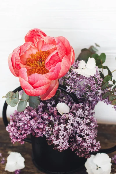 Güzel şakayık, leylak çiçekleri ve okaliptüs, taşra arka planında kaliteli metal sulama düzenlenebilir. Anneler Günün kutlu olsun ya da Sevgililer Günü. Merhaba bahar. Modern çiçekler hala hayat