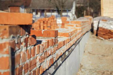 Beton temeli çimento kaplı tuğlalar, ev inşa süreci. Beton temeller üzerine döşenmiş kırmızı tuğlalar. İnşaat alanında inşaat malzemeleri