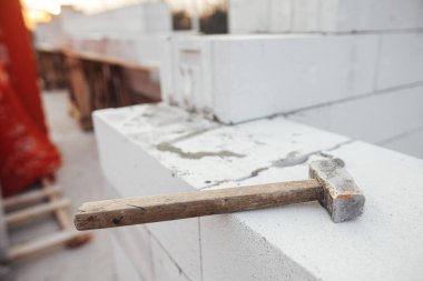 Otoklavla havalandırılmış beton bloklarda çekiç. Beyaz blokları yakınlaştırıyor. Masonluk. İnşaat alanındaki ev inşaatı