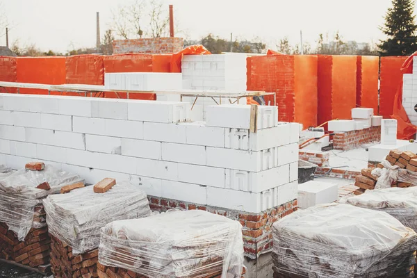 Autoclaved aerated blocks on concrete foundation, process of house building. Stacks of white aerated blocks for laying on concrete foundation. Building materials at construction site