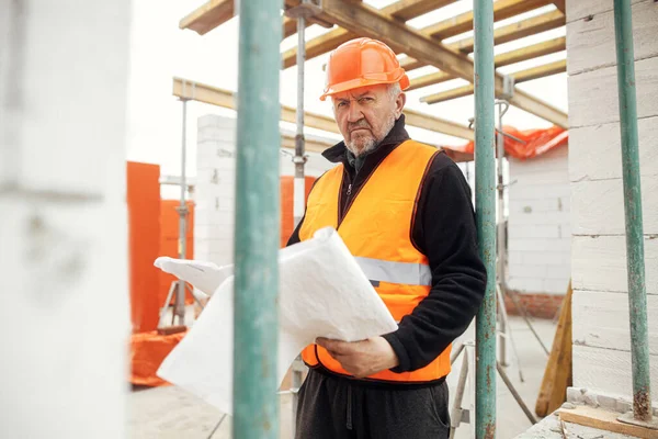 Son sınıf erkek ustabaşı yeni modern evin planlarını kontrol ediyor. İnşaat alanındaki planlara bakan mühendis ya da inşaat işçisi. Boşluğu kopyala