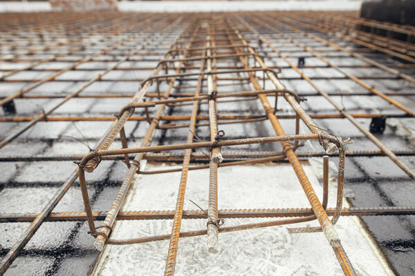 Steel rebar mesh close up. Reinforcement rods at construction site. Rusty steel reinforcement bars for concrete foundation or ceiling. Process of house building