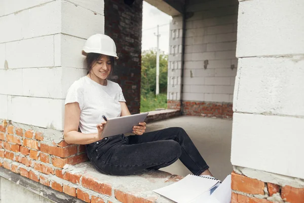 Young Female Architect Tablet Checking Blueprints While Sitting Window New — стоковое фото