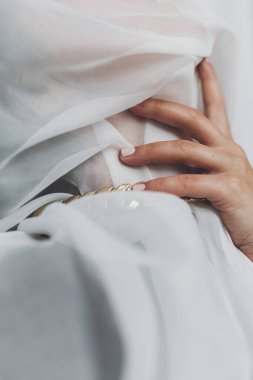 Hafif kumaş ve el ele tutuşmuş genç bir kadının portresi. Kişisel bakım konsepti. Sosyal izolasyon ve baskı. Odada altın kolyeyle poz veren şehvetli bir kadın. Boğulmak.