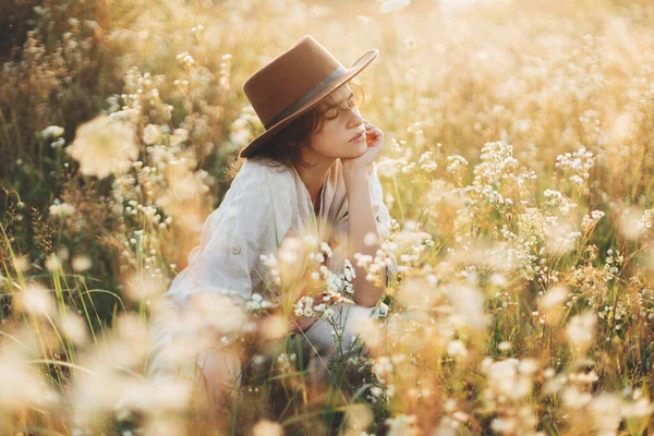 Şık Şapkalı Kadın Gün Batımında Kır Çiçeklerinin Arasında Oturuyor Yaz — Stok fotoğraf