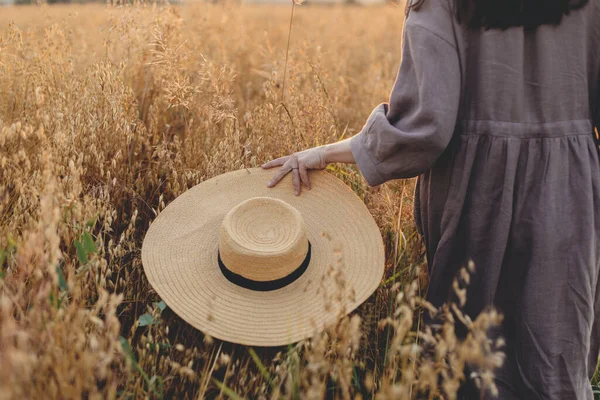 Hasır Şapkalı Şık Bir Kadın Güneş Işığında Yulaf Tarlasında Yürüyor — Stok fotoğraf