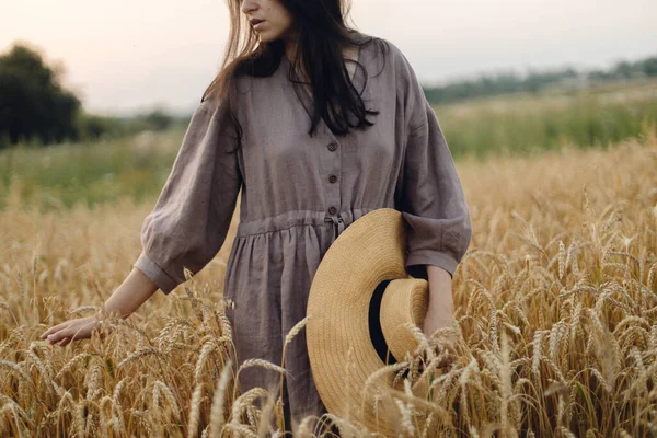 黄昏时分 站在麦田里戴草帽的时髦女人 大气宁静的时刻 在夏夜的乡间 穿着粗俗亚麻布衣服的年轻女性显得很休闲 农村缓慢的生活 — 图库照片