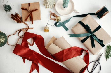 Mutlu Noeller ve mutlu tatiller! Şık noel hediyelerini paketlemek düzdü. Modern noel hediyesi kutusu, kurdeleler, el işi kağıt ve beyaz ahşap üzerine süslemeler. Estetik kış tatili