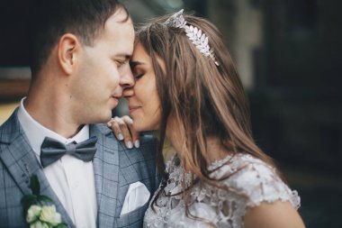 Eski kilisenin arka planında öpüşen ve kucaklayan şık gelin ve damadın portreleri. Romantik bir an. Provence düğünü. Güzel, şehvetli bir düğün çifti Avrupa şehrinde nazikçe sarılıyor.