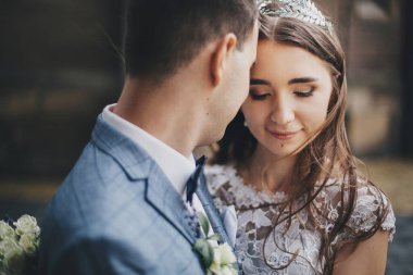 Eski kilisenin arka planına sarılmış şık gelin ve damadın portreleri. Romantik bir an. Provence düğünü. Güzel, şehvetli bir düğün çifti Avrupa şehrinde nazikçe sarılıyor.