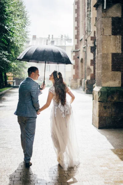 Стильная Невеста Жених Гуляют Зонтиком Целуются Фоне Старой Церкви Дождем — стоковое фото