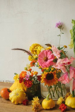 Stylish autumn composition against rustic background. Colorful autumn flowers, pumpkins, pattypan squashes still life. Seasons greeting card. Harvest in countryside. Happy Thanksgiving