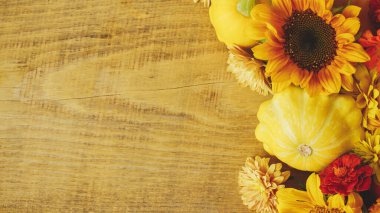 Autumn rustic banner. Colorful autumn flowers, pumpkins, pattypan squashes on wooden table. Seasons greeting card template, space for text. Harvest in countryside. Happy Thanksgiving!