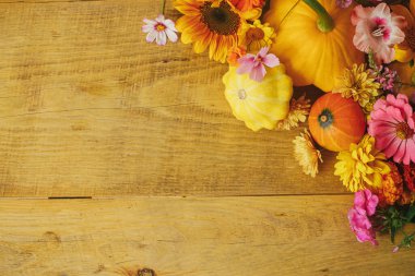 Stylish autumn composition. Colorful autumn flowers, pumpkins, pattypan squashes on rustic wooden table. Seasons greeting card template, space for text. Harvest in countryside. Happy Thanksgiving!