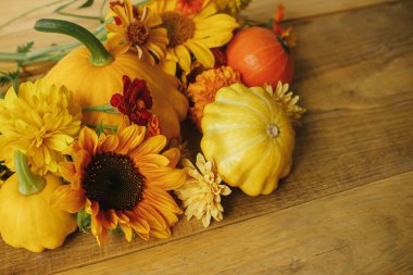 Happy Thanksgiving! Stylish autumn composition on rustic background. Colorful autumn flowers, pumpkins, pattypan squashes on wooden table. Seasons greeting card, space for text. Hello Fall