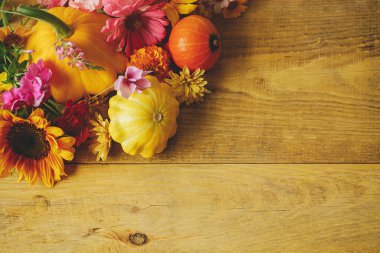 Stylish autumn composition. Colorful autumn flowers, pumpkins, pattypan squashes on rustic wooden table. Seasons greeting card template, space for text. Harvest in countryside. Happy Thanksgiving!