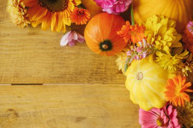 Autumn rustic banner. Colorful autumn flowers, pumpkins, pattypan squashes on wooden table. Seasons greeting card template, space for text. Harvest in countryside. Happy Thanksgiving!