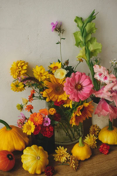 Happy Thanksgiving! Autumn moody still life, atmospheric image. Colorful autumn flowers, pumpkins, pattypan squashes composition against rustic wall. Harvest in countryside. Hello Fall,
