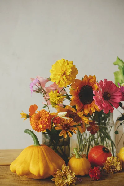 Happy Thanksgiving! Colorful autumn flowers, pumpkins, pattypan squashes composition on wooden table against rustic background. Seasons greeting card. Harvest in countryside. Hello Fall