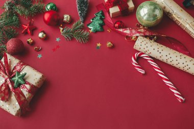 Noel yatağı. Şık bir Noel hediyesi, altın ambalaj kağıdı, kurdele ve kırmızı arka planda şenlikli süslemeler. Mevsimlik tebrik kartı şablonu ve metin için boşluk. İyi tatiller. !